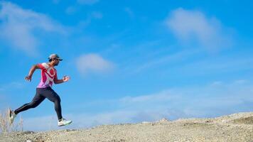 Man Running Outdoors on a Rocky Terrain Under a Clear Blue Sky on a Sunny Day photo