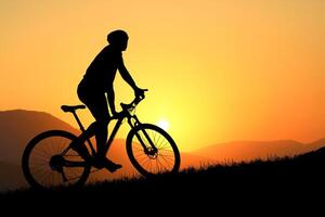 Silhouette of a Cyclist Riding a Mountain Bike at Sunset with a Vibrant Orange Sky and Sun in the Background photo
