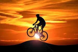 Silhouette of a Cyclist Performing a Jump Against a Vibrant Sunset Sky with Dramatic Clouds photo