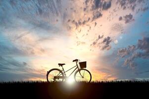 Silhouette of Bicycle Against a Stunning Sunset Sky with Dramatic Clouds and Vibrant Colors in the Background photo
