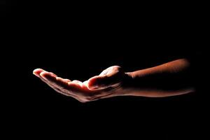 Outstretched Hand in Dramatic Lighting Against a Black Background, Symbolizing Help, Support, and Connection in a Minimalist and Artistic Style photo