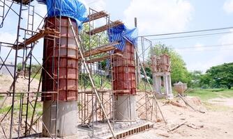 Construction Site with Concrete Columns and Scaffolding Under Blue Sky - Infrastructure Development and Building Progress in a Rural Area photo
