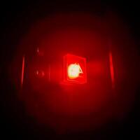 close up view of a button with bright red light shining in the dark background photo