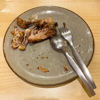 used dinner plates with spoons, forks and the remains of used chicken bones photo