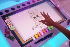 A small child is drawing and coloring a picture of squid using a game screen photo