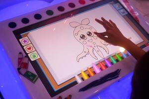A small child is drawing and coloring a picture of squid using a game screen photo