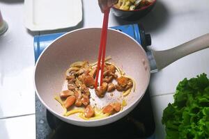 Someone was using chopsticks to turn the chicken that was being grilled photo