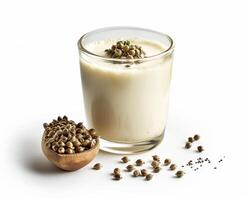 a glass of milk with hemp seeds on a wooden spoon photo