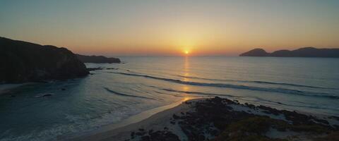 Behold the captivating beauty of a secluded beach at dawn, where the first light of day bathes the landscape in a soft, golden glow. photo
