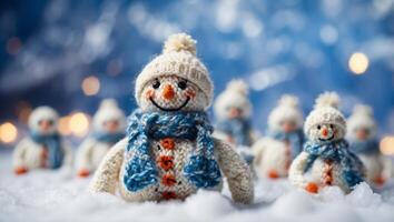 Little knitted snowmen on the white snow on blue background. photo