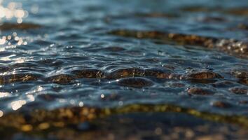 Ripples of the crystal clear shallow water surface, on a stony beach of Lake outdoor summer backgrounds. photo