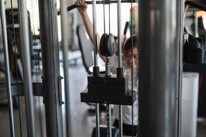 A young man is working out on a weight machine photo