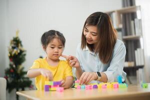 Asian woman and a child are playing with blocks. The woman is helping the child build a tower photo