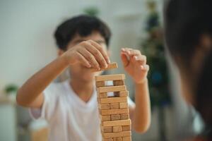 A young boy is playing with a wooden block tower. He is focused on the tower and he is enjoying himself photo