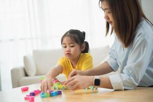 Asian woman and a child are playing with blocks. The woman is helping the child build a tower photo