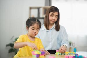Asian woman and a child are playing with blocks. The woman is helping the child build a tower photo