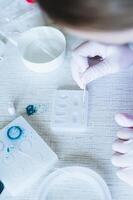 Female hands in gloves decorate earrings made of epoxy resin in the form vertical view photo