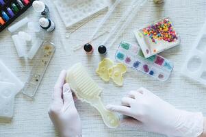 Female hands in gloves hold a mold for making a comb from epoxy resin photo