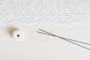 Knitting background, finished texture, ball and knitting needles on a light background top view photo