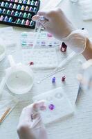 Children's hands in gloves fill a crystal mold with epoxy resin from a pipette vertical view photo