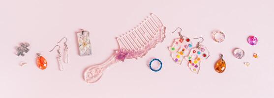 Earrings, pendants, rings, comb and other jewelry made of epoxy resin on a pink top view web banner photo
