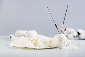 A ball of thread, hooks and an uncrocheted knitting on a blue table photo