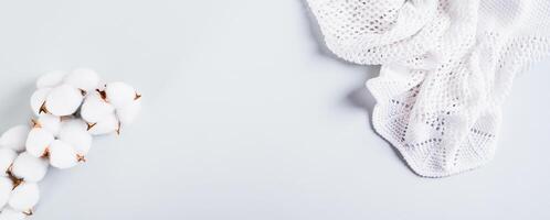 Texture knitted fabric and cotton branch on blue background web banner photo