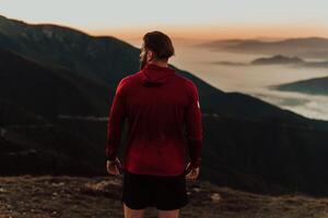 An athlete rests on top of a mountain after exhausting running training. photo