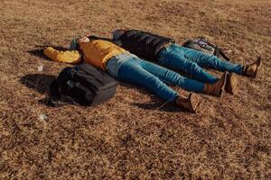 a happy couple lying on a meadow while resting on top of a mountain photo