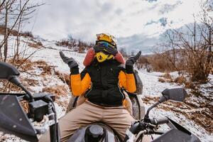 Couple enjoying while driving quad bike on top of mountain at winter time photo