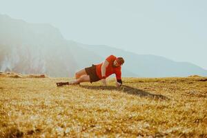A man doing abs exercises on top of a mountain photo