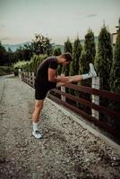 Athlete performing leg stretching exercises after a run in a natural environment. Fitness themed photograph showcasing physical activity flexibility and health. photo