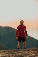An athlete rests on top of a mountain after exhausting running training. photo