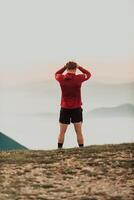 An athlete rests on top of a mountain after exhausting running training. photo
