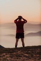 An athlete rests on top of a mountain after exhausting running training. photo