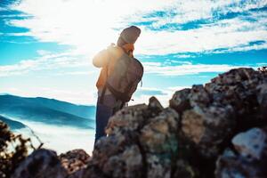 Cheering woman backpacker enjoy the view on sunrise mountain top cliff edge photo