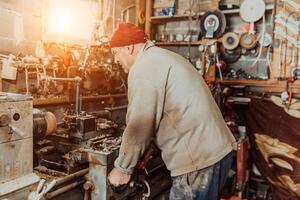A senior man procesing wood on a lathe and making wooden dishes in the workshop photo