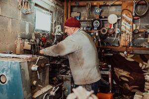 A senior man procesing wood on a lathe and making wooden dishes in the workshop photo