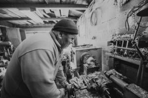 A senior man procesing wood on a lathe and making wooden dishes in the workshop photo