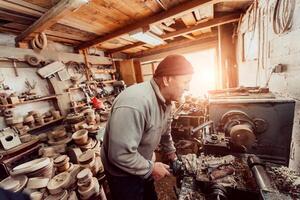 A senior man procesing wood on a lathe and making wooden dishes in the workshop photo
