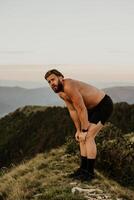 An athlete rests on top of a mountain after exhausting running training. photo