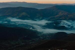 Mountain range with visible silhouettes through the morning colorful fog photo