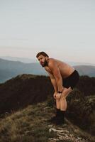 An athlete rests on top of a mountain after exhausting running training. photo