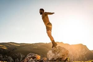 Man doing conditioning training on top of a mountain in the early morning with the sunrise in the background photo