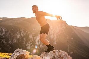 Man doing conditioning training on top of a mountain in the early morning with the sunrise in the background photo