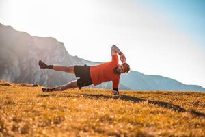 A man doing abs exercises on top of a mountain photo