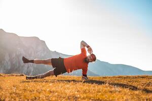 A man doing abs exercises on top of a mountain photo