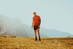An athlete rests on top of a mountain after exhausting running training. photo