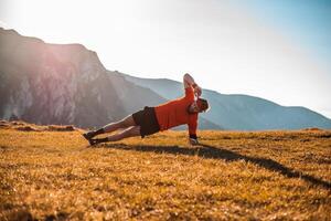 A man doing abs exercises on top of a mountain photo