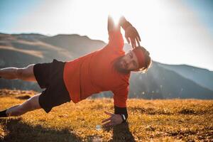 A man doing abs exercises on top of a mountain photo